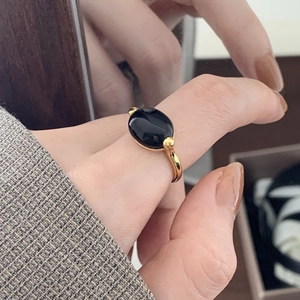 Detail of a vintage gold ring featuring a large oval black onyx stone worn on finger