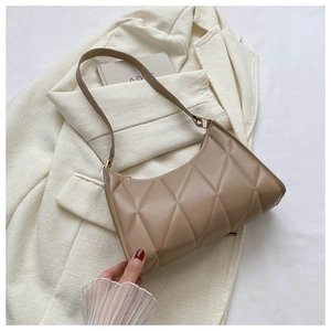 Detail of khaki quilted shoulder bag with diamond stitching on a white blazer