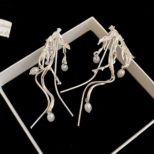 Detailed macro of silver irregular tassel earrings with dangling white pearls in a box