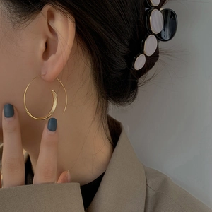 Matte gold spiral geometric hoop earrings with a textured finish on model