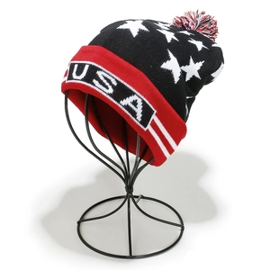 Detail of USA knit beanie featuring white stars on black background and red pompom