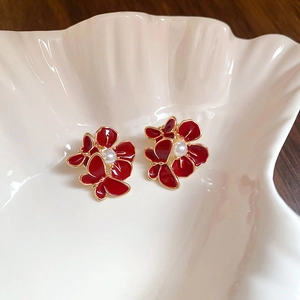 Macro shot of red floral butterfly earrings with pearls on a shell ceramic plate