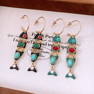 Close-up of vintage enamel fish tassel earrings in black and deep green on a display card