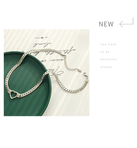 Détail macro du collier chaîne cubaine argentée avec pendentif cœur évidé minimaliste