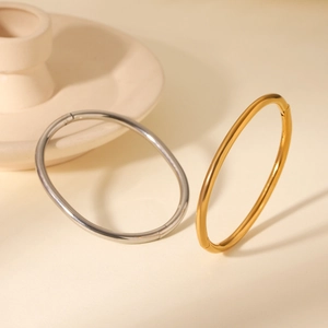 Detailed view of minimalist oval hinged bangles in polished gold and silver finishes