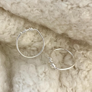 Detail of two silver S925 sterling silver spiral open rings on white knitted texture