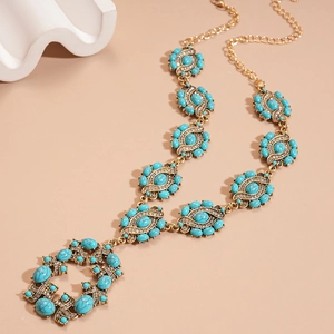 Détail de collier bohème doré serti de résine turquoise et de strass brillants