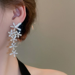 Close-up of silver tassel earrings with zircon flower design on female model