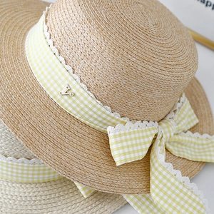 Summer straw hat with yellow plaid ribbon and lace trim shown from a stylish top angle