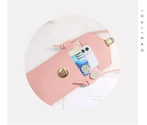 Detail view of pink vertical crossbody phone bag featuring gold twist lock and card slots