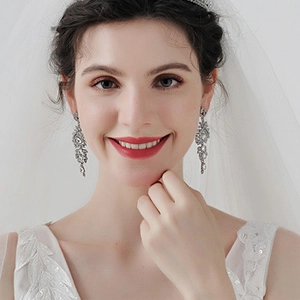 Macro detail of bridal silver rhinestone dangle earrings worn by a bride for wedding