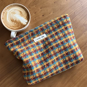 Close-up of colorful houndstooth tweed cosmetic bag on a wooden table with coffee