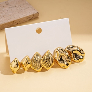 Detail of six-piece golden geometric earrings set with polished textures on card