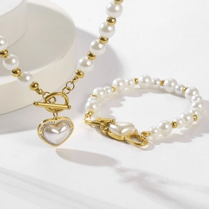 Detail of heart pearl pendant with crystal edge on gold necklace and bracelet set