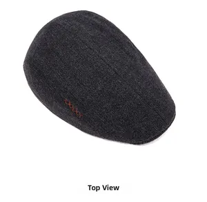 Detailed top view of grey knit wool flat cap featuring orange cross-stitch accents