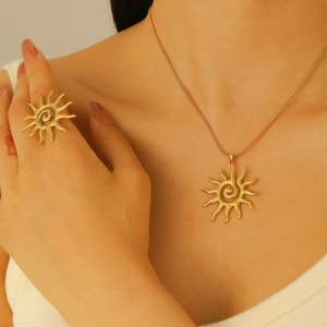 Detail of golden sun pendant necklace and ring with hammered metal texture on model