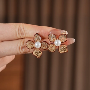 Detail eines Vintage-Blumenohrrings mit weißer Perle auf dunklem Stoffhintergrund