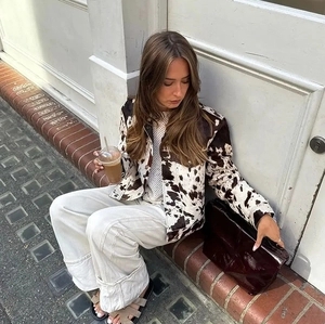 Stile street di una giacca patchwork stampa mucca con jeans bianchi larghi e borsa