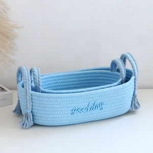 Detail of light blue woven cotton rope baskets with tassels and goodday embroidery