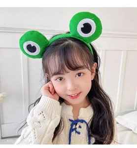 Close-up of a young girl wearing a cute green plush frog headband with large eyes