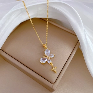 Luxurious gold butterfly necklace with crystal cross pendant on beige jewelry box
