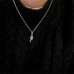 Minimalist silver knot necklace pendant with delicate cross chain on black sweater