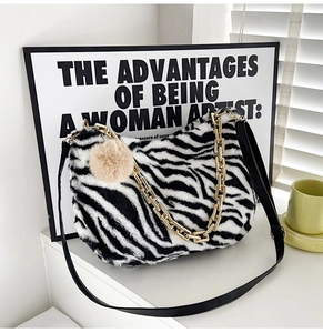 Detailed shot of zebra pattern plush tote with gold chain and faux fur ball charm