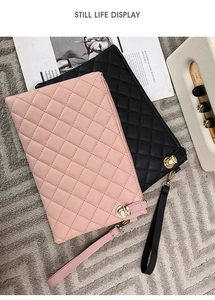 Detail of pink and black quilted PU leather clutch bags with gold twist locks on a rug