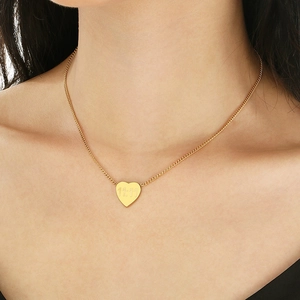 Détail d'un collier pendentif cœur doré avec gravure 11:11 porté par un mannequin