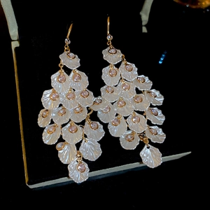 Detailed view of long tiered white petal earrings with pink stones on a black case