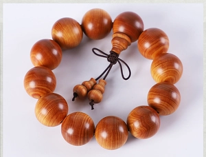 Close-up of polished Thuja wood prayer beads with traditional brown tassel and knot