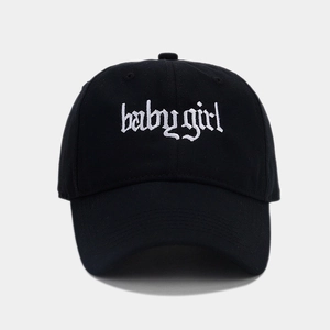 Detail of white Babygirl gothic embroidery on black cotton baseball cap fabric