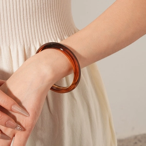 Detail of amber brown resin bangle with translucent finish on a woman wrist