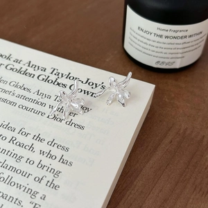 Close-up of lily flower stud earrings in 925 silver on vintage book pages