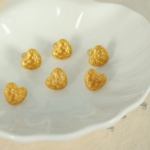 Set of six vintage French gold braided heart earrings displayed on a white shell-shaped tray