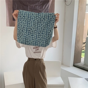 Close-up of floral canvas shoulder bag with blue small flower texture held by model