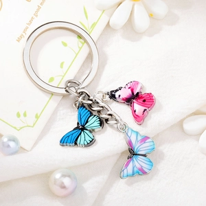 Colorful butterfly alloy keychain with pink and blue enamel pendants on white fabric