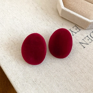 Vue macro des boucles d'oreilles ovales en velours rouge vin à texture mate