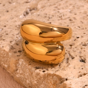 Close-up of a chunky 18K gold plated geometric ring on a textured stone surface