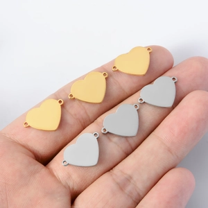 Polished gold and silver heart-shaped connectors shown on a hand for size scale