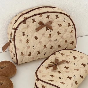 Detail of quilted cosmetic bag set featuring brown bear prints and ribbon decorations