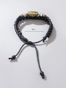 Detail view of handmade braided cord necklace with black beads and gold-tone pendant