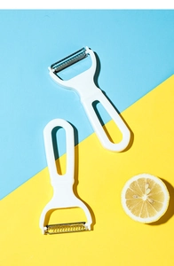 Close-up of dual-blade vegetable peelers with white handles on a colorful background