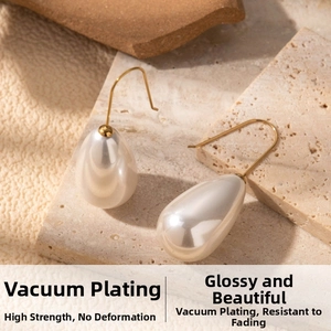 Detailed close-up of gold-plated teardrop pearl earrings on a textured stone surface