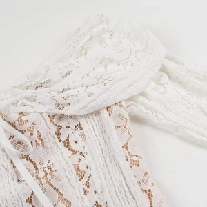 Close-up of white crochet lace dress with beige lining and side lace-up detail
