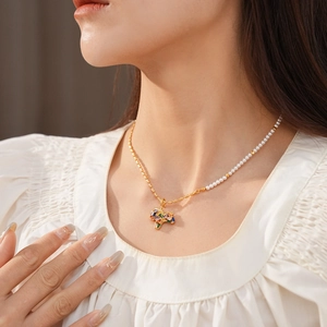 Detail of vintage gold horse necklace with white pearls and colorful zircons on a model