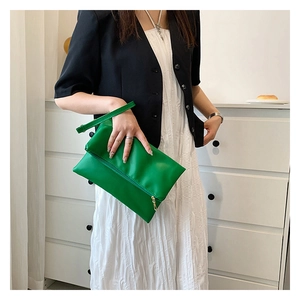 Dettaglio di borsa a mano in pelle verde brillante con cerniera dorata e manico