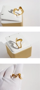 Detail of irregular wave gold-plated ring on white holder and worn with white gloves