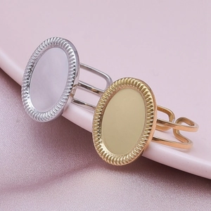 Detailed view of adjustable gold and silver oval ring bases on pink satin background