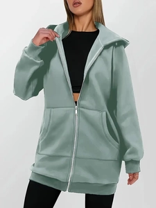 Close-up of sage green hoodie featuring functional front pockets and a full zipper closure